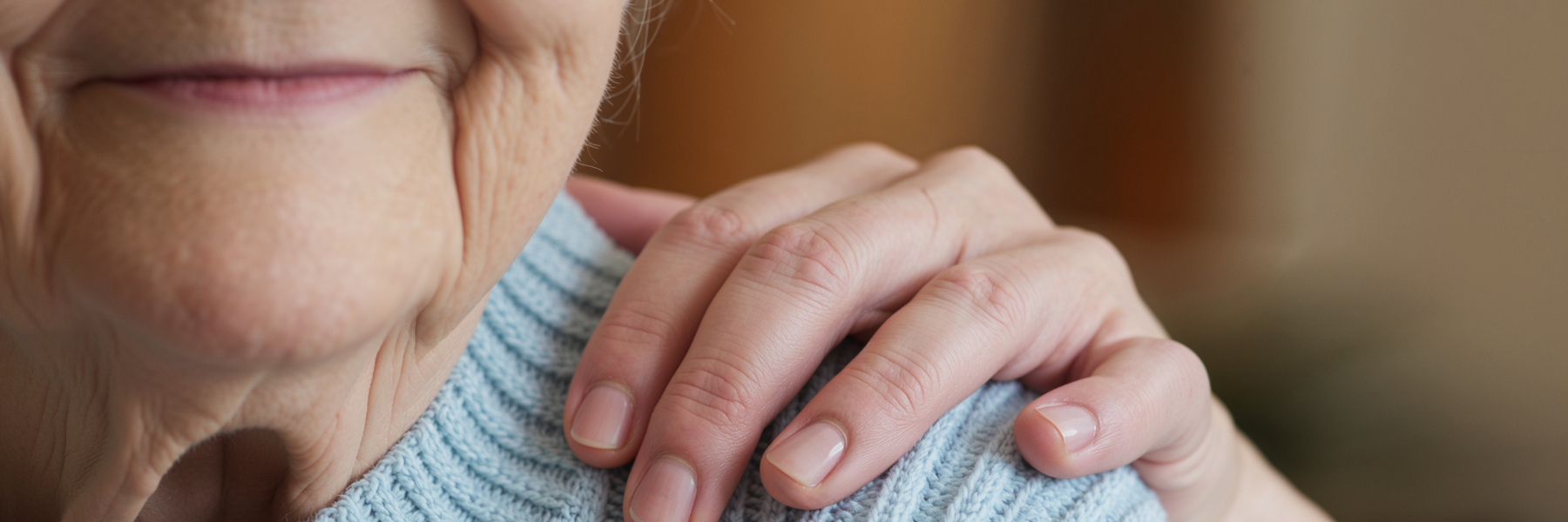 Image of a woman's hand on an elderly woman's shoulder to show comfort in response to power of attorney abuse in North Carolina